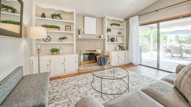 Een woonkamer met een open haard, witte planken, een glazen salontafel en uitzicht op de omgeving.
