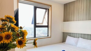 Ett hotellrum med en säng, ett fönster med utsikt och en vas med solrosor.