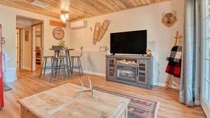 Una sala de estar con techo de madera, televisor, chimenea y una estatua de perro.