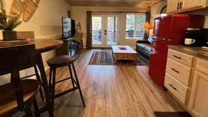Una cocina con suelo de madera, un refrigerador rojo y una zona de comedor con mesa y sillas.