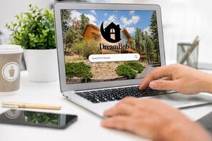 A laptop displaying a website with a wooden cabin and a search bar.