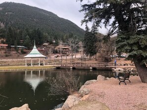 A tranquil park with a pond, a gazebo, and a bridge.