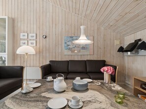 A modern living room with a wooden ceiling, a brown leather sofa, a marble coffee table with tea set, and a painting on the wall. - "Sylvia" - 900m from the sea by Interhome (Nexø)