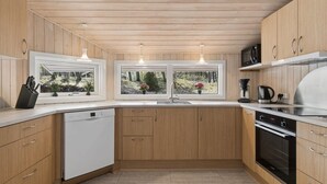 A modern kitchen with wooden cabinets, a dishwasher, a stove, and a coffee maker. - "Sylvia" - 900m from the sea by Interhome (Nexø)