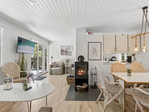 A modern interior with a fireplace, dining area, kitchen, and a TV mounted on the wall.