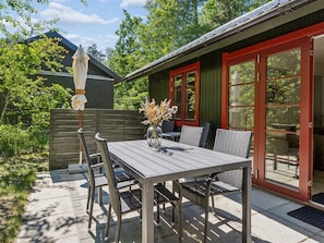A patio with a table and chairs, a vase with flowers, and a wooden fence.