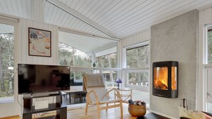 Een moderne woonkamer met een televisie, een open haard en uitzicht op de omgeving.