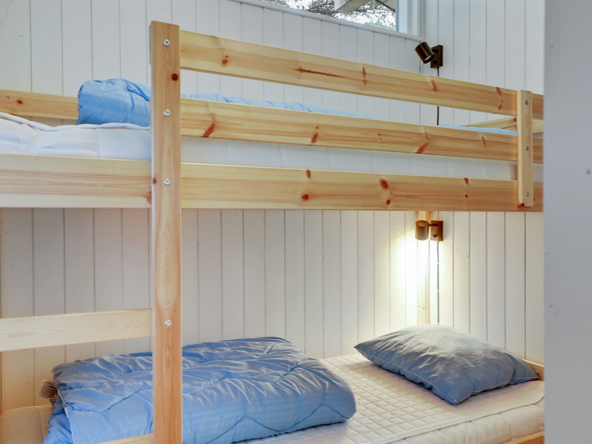 Un lit superposé avec une structure en bois et une literie bleue.