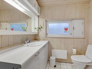 A bathroom with wooden paneling, a white sink, a mirror, a window with a heart-shaped sticker, and a toilet. - "Gaja" - 1km from the sea by Interhome (Nexø)