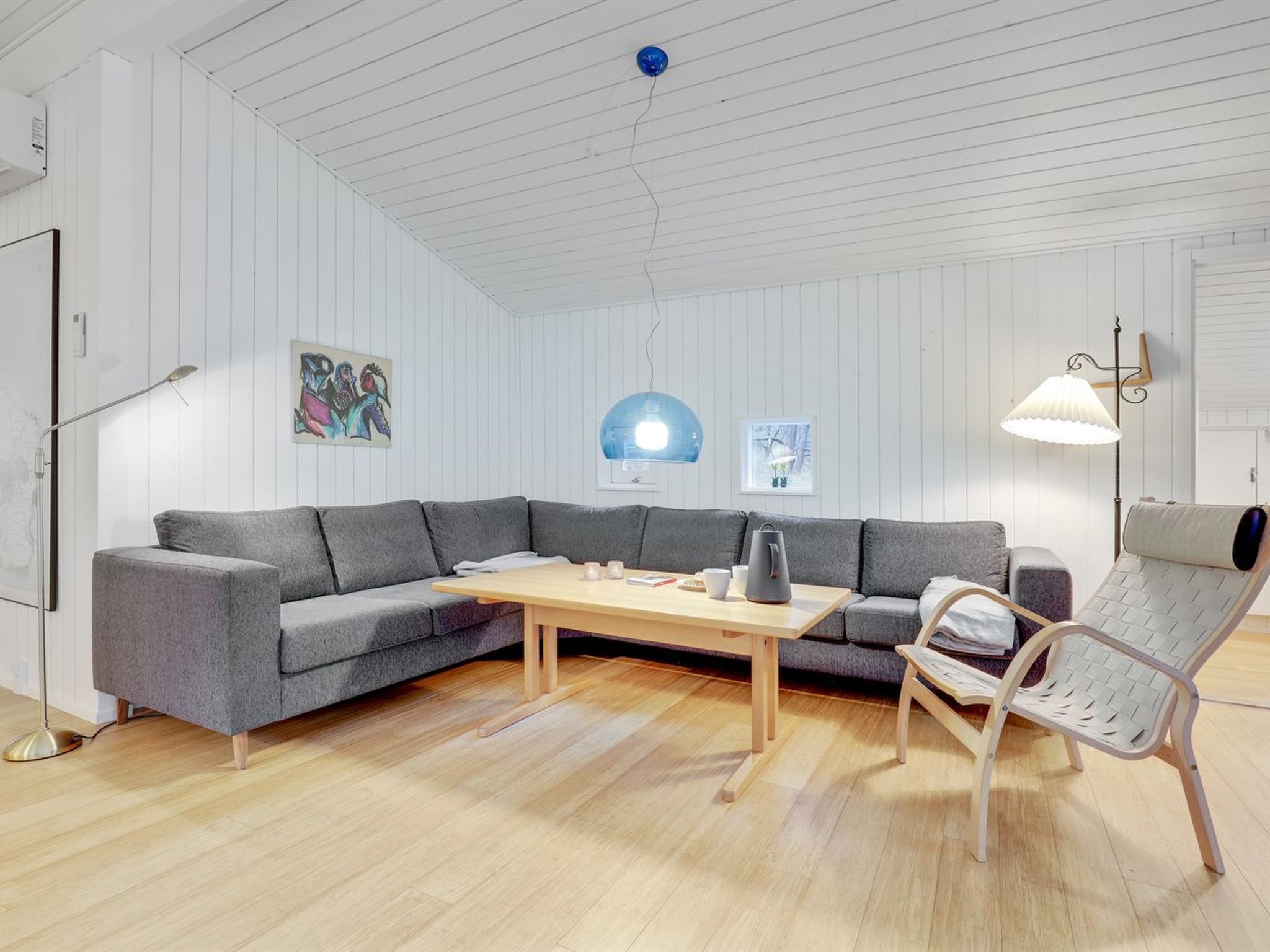 Una sala moderna con un sofá seccional gris, una mesa de centro de madera y un sillón blanco.