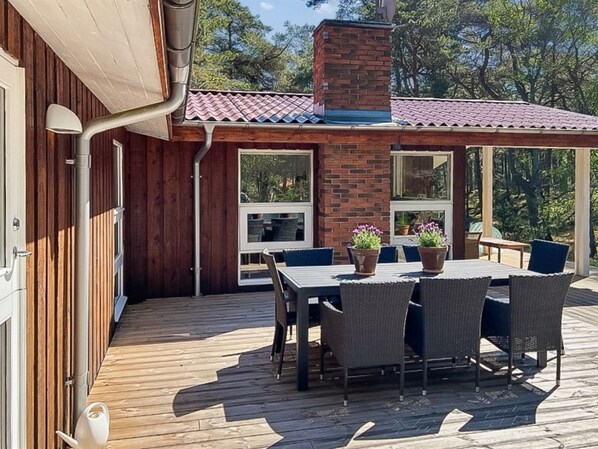 A wooden deck with a table and chairs, a brick chimney, and large windows. - "Gaja" - 1km from the sea by Interhome (Nexø)