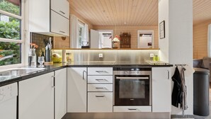 A modern kitchen with white cabinets, a stainless steel oven, and a black countertop. - "Nahuel" - 200m from the sea by Interhome (Nexø)