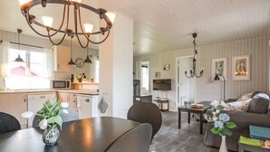 Eine moderne Küche mit Essbereich, ein Wohnzimmer mit Sofa und Fernseher sowie ein Kronleuchter.