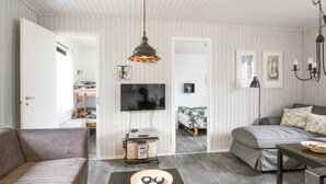 Ein modernes Wohnzimmer mit Sofa, Couchtisch, Fernseher und Essbereich mit Tisch und Stühlen.