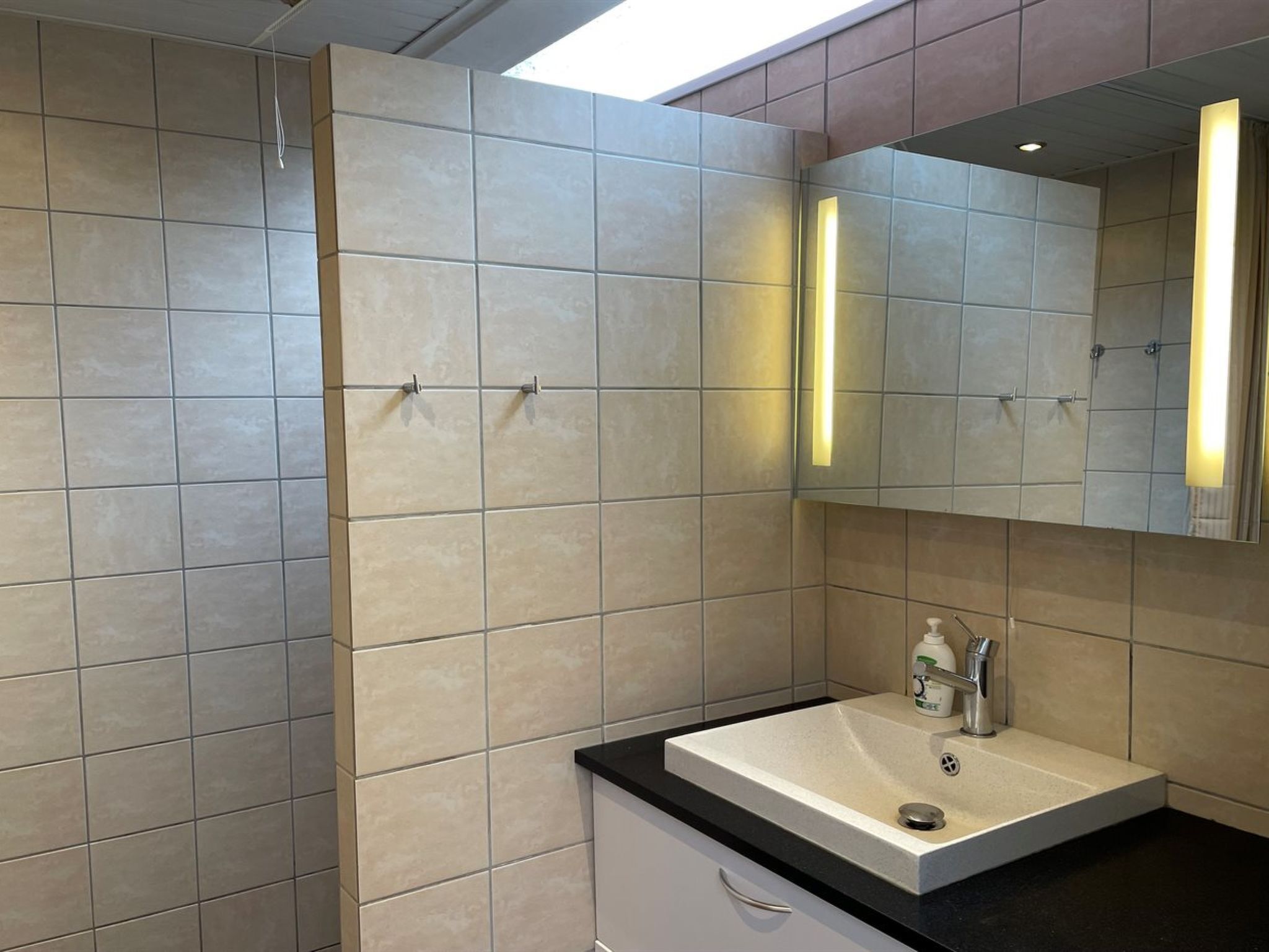 Un baño moderno con un espejo grande, un lavabo y una zona de ducha.
