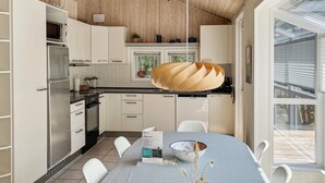 Eine moderne Küche mit weißen Schränken, einem Edelstahl-Kühlschrank und einem Essbereich mit gestreiftem Tischleinen.