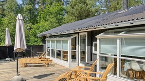 Eine Holzterrasse mit Sitzgelegenheiten und einem überdachten Bereich.