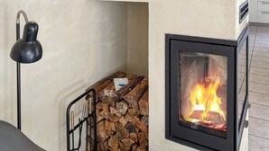 Eine moderne Küche mit Kaminofen, Metalllampe und Holzstoß.