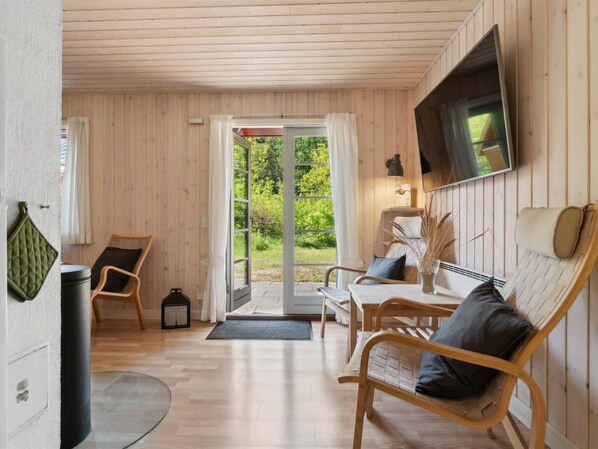 A cozy room with wooden walls and floors, a sofa, a table, and a TV mounted on the wall.