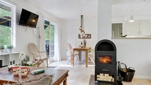 A cozy living room with a fireplace, a dining area, and a TV mounted on the wall. - "Selvi" - 125m from the sea by Interhome (Nexø)