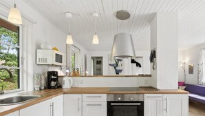A modern kitchen with white cabinets, a Bosch oven, pendant lights, and a view of the outdoors. - "Georg" - 300m from the sea by Interhome (Nexø)