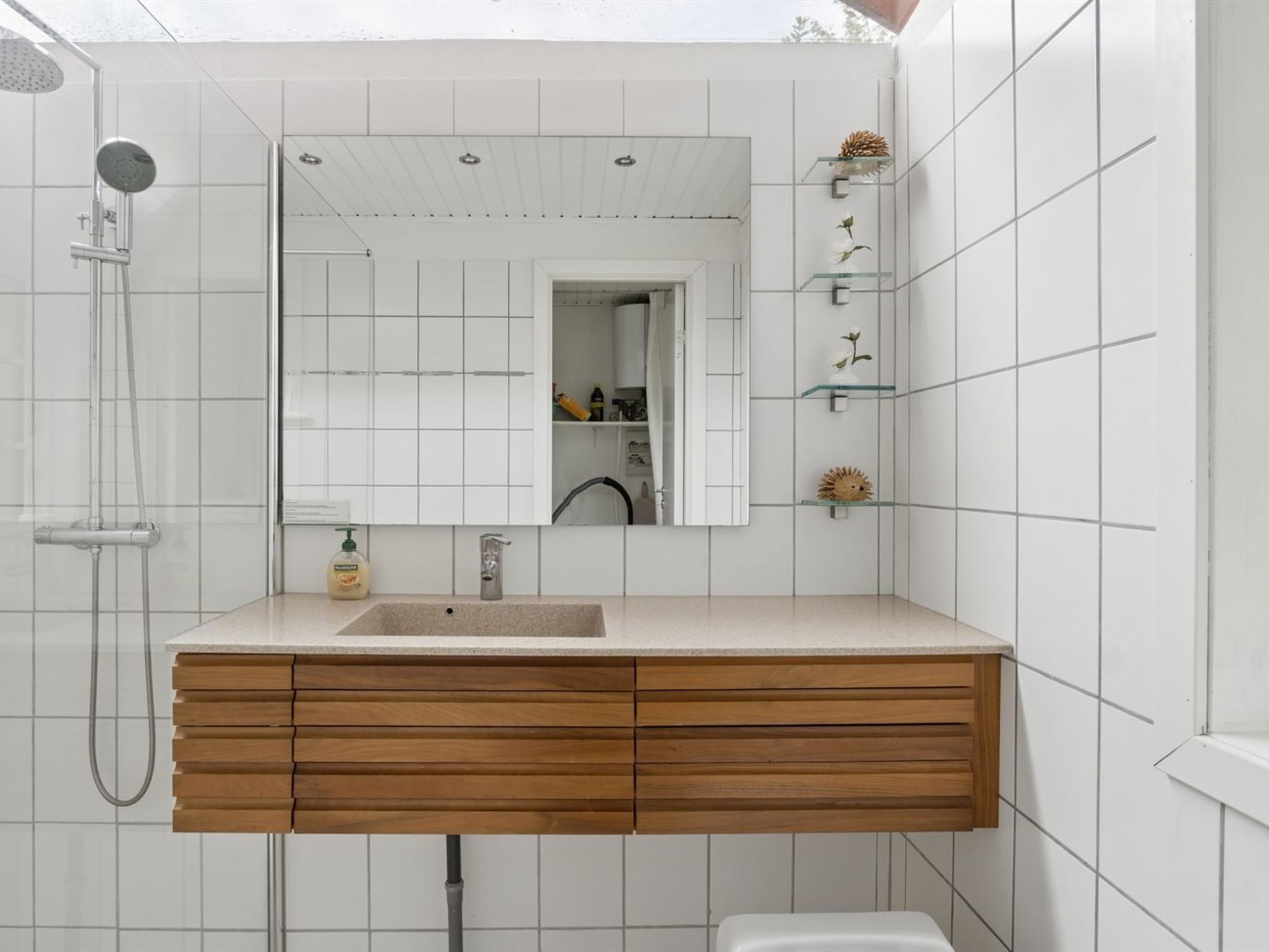 Une salle de bain avec un meuble-lavabo en bois, un grand miroir et une douche.