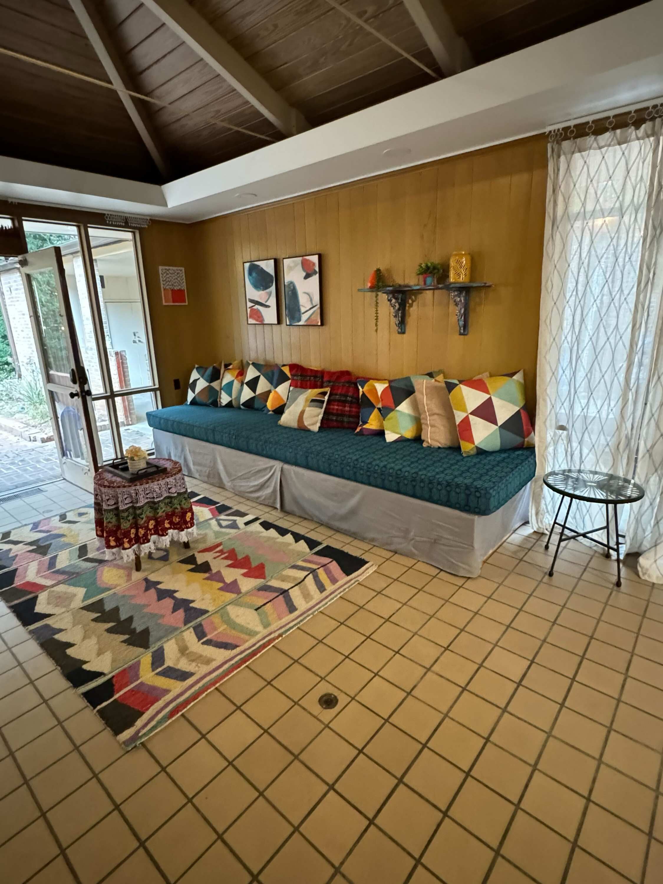 Um quarto acolhedor com sofá, almofadas estampadas, uma mesinha e um tapete.