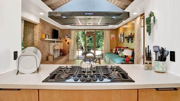 A modern kitchen with a gas stove, a brick wall, and a large window. - Midcentury Modern -Hot Tub - Retro Retreat (Mobile)