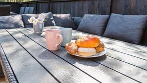Ein Holztisch mit einer Platte Gebäck, zwei Tassen und einem kleinen Blumentopf.