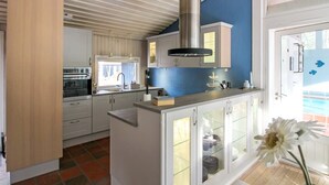 A modern kitchen with white cabinetry, a stainless steel range hood, and a window providing natural light. - "Dagi" - 300m from the sea by Interhome (Nexø)