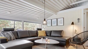 A modern living room with a sectional sofa, a round coffee table, and a wicker chair. - "Dagi" - 300m from the sea by Interhome (Nexø)