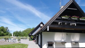 Un edificio con techo inclinado, mesas al aire libre y una antena parabólica.