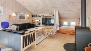 A cozy living room with a black sofa, a small table, a TV, and a fireplace.
