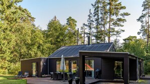 En moderne hytte med terrasse, udendørs møbler og udsigt over den omkringliggende skov.