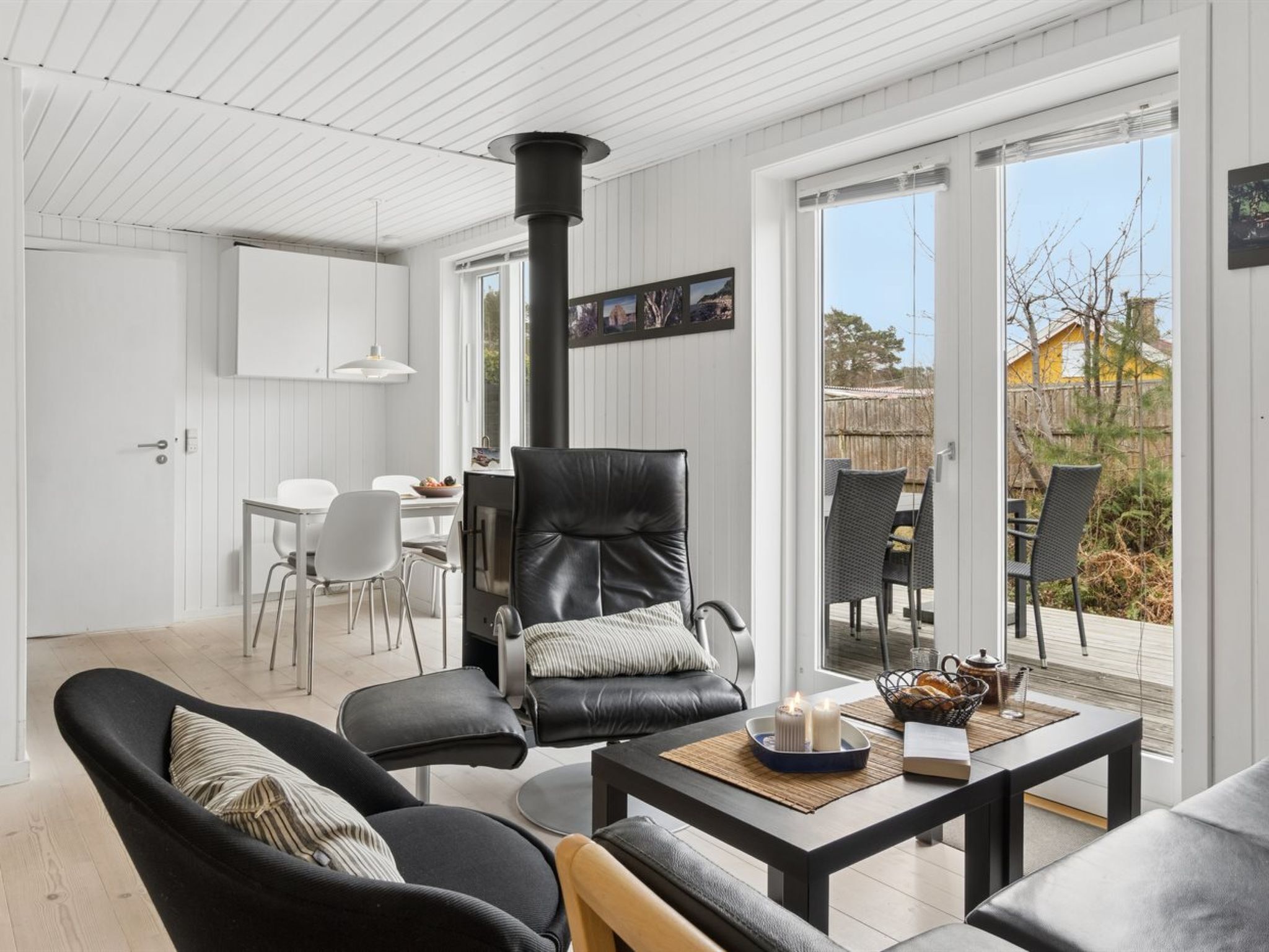 Ein modernes Interieur mit Kamin, Ledersesseln, einem Essbereich und Blick durch Glastüren.