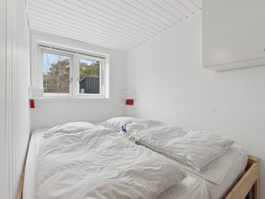 Et soveværelse med en enkeltseng, et vindue med udsigt til træer og et hvidt loft.