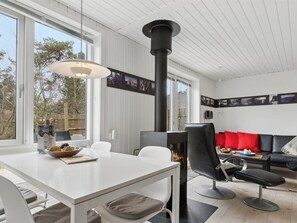 En moderne stue med pejs, hvide møbler og et spiseområde med bord og stole.