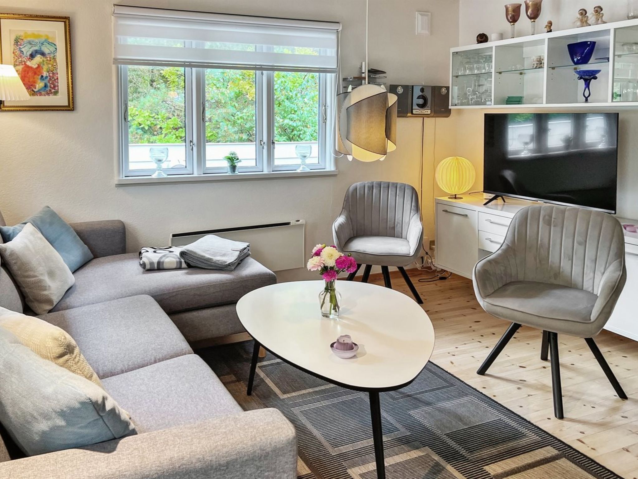 A modern living room with a grey sofa, a round coffee table, and a television.
