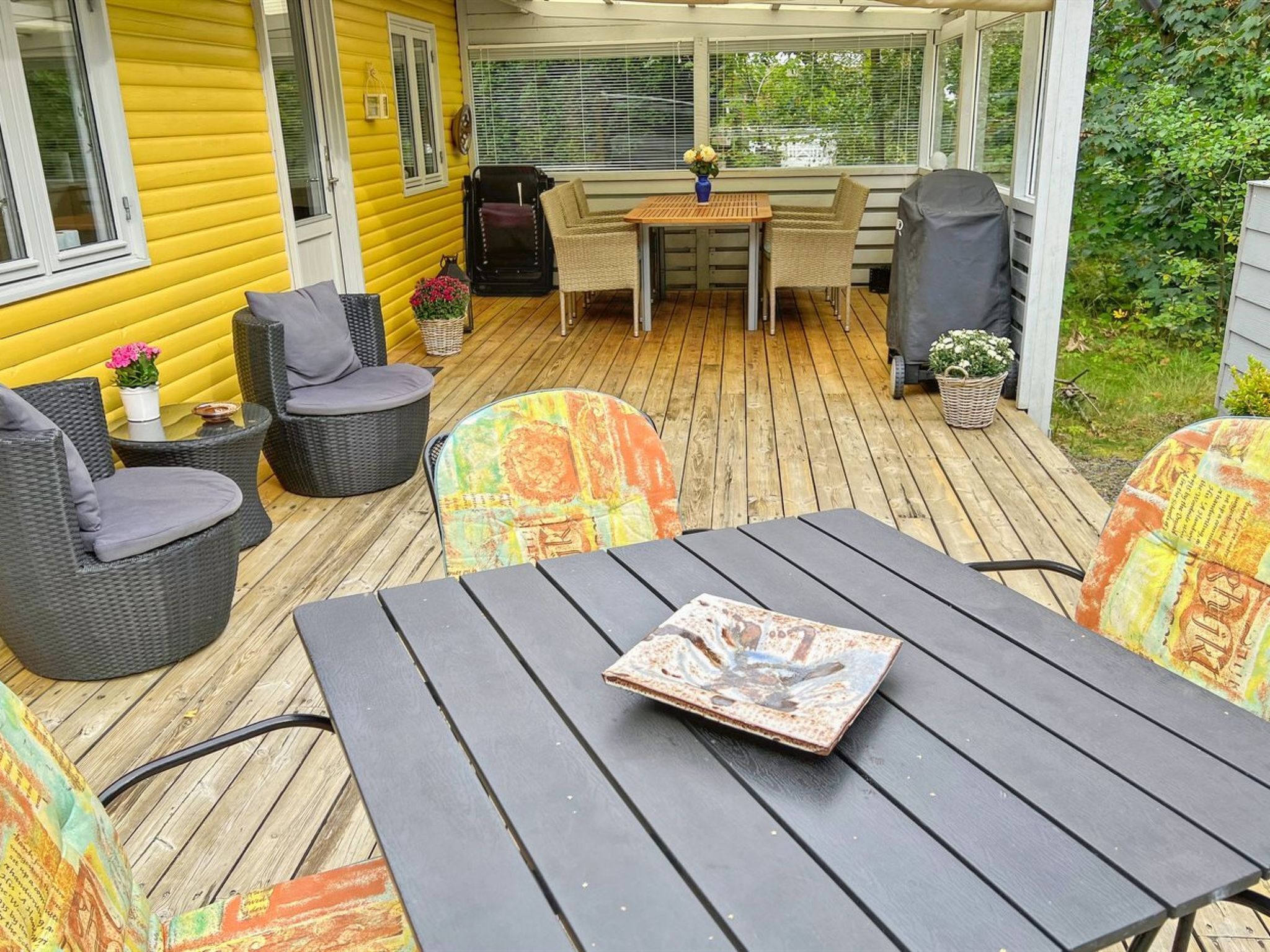 Une terrasse couverte avec une plateforme en bois, du mobilier d’extérieur et une table sur laquelle est posé un livre.