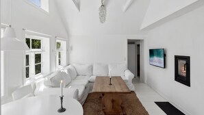 Ein geräumiges Zimmer mit einem weißen Sofa, einem Holztisch und einer Kristallleuchter.