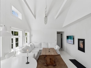 A spacious room with a white sofa, a wooden table, and a chandelier.