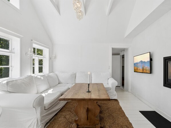 A modern living room with a white sofa, a wooden coffee table, and a large window.
