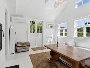 A bright room with a wooden table, white walls, and a white sofa.
