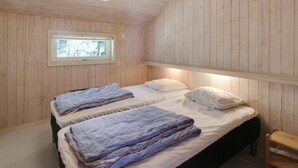 Ein Schlafzimmer einer Holzhütte mit zwei Betten, einem Fenster und einer Hängeleuchte.
