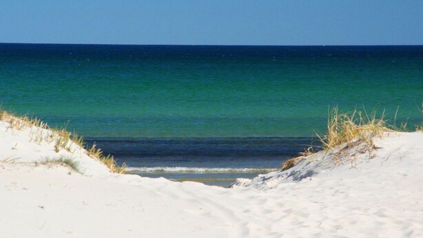 En strand med vit sand och fri utsikt över havet.