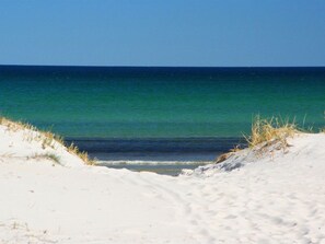 A beach with white sand and a clear view of the ocean.