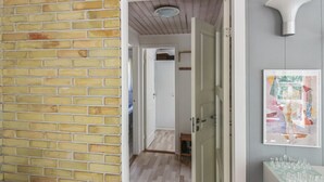 A hallway with a brick wall, a door leading to another room, and a glass display case with items on top. - "Kjeld" - 900m from the sea by Interhome (Nexø)