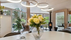 A modern interior with a dining table, a vase of flowers, and a fireplace. - "Bergulv" - 75m from the sea by Interhome (Nexø)