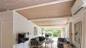 A spacious living room with a wooden ceiling, white paneled walls, a flat-screen TV, a sofa, a coffee table, and a desk with a computer. - "Zeytun" - 800m from the sea by Interhome (Nexø)