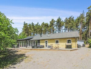 Eine Lodge mit überdachter Außenbereich-Sitzgelegenheit, einer kleinen Veranda und einem Schotterweg.